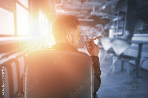 Composite image of rear view of male executive holding cigar photo