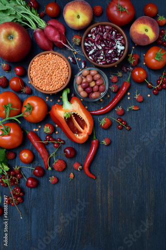 composition of red vegetarian product: fruits, vegetables and beans on wooden background. Apples, tomatoes, currants, radishes, peppers, raspberries, cherry, lentils. Healthy food. Copy space for text