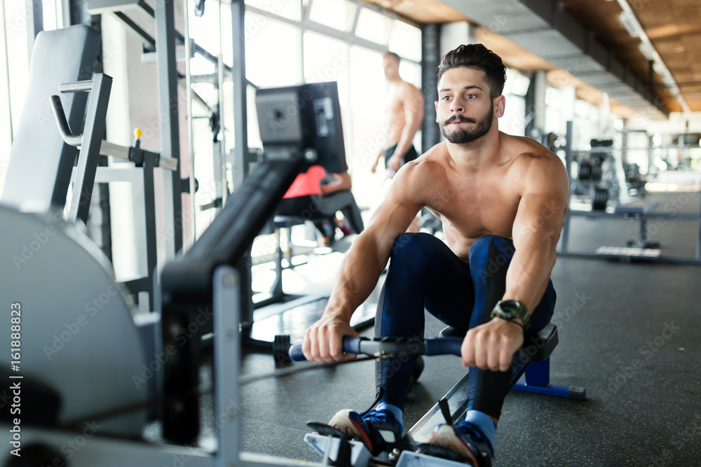 Fototapeta premium Young handsome man workout with rowing machine