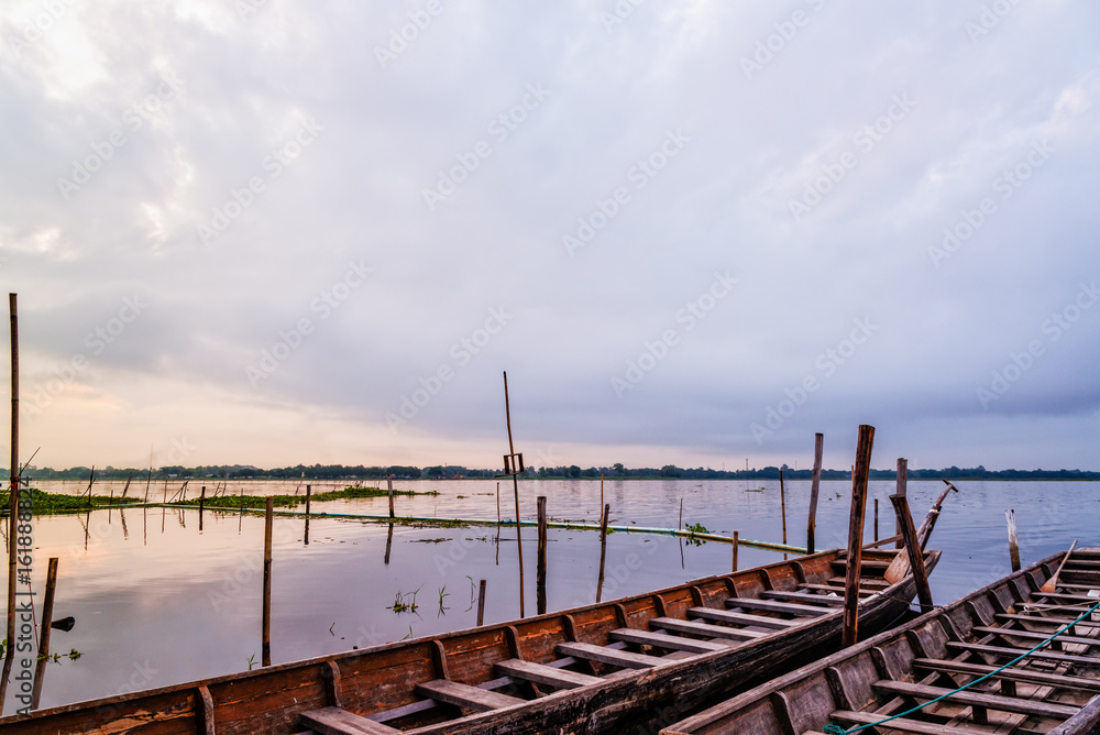 Old wooden boat floating on the water amidst the natural landscape of the morning at Kwan Phayao Lake in Phayao Province, Thailand Old wooden boat floating on the water amidst the natural landscape of the morning at Kwan Phayao Lake in Phayao Province, Thailand