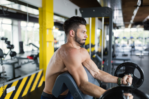 Athlete muscular bodybuilder in gym training biceps