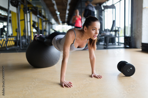 Young woman exercising with swiss ball in gym