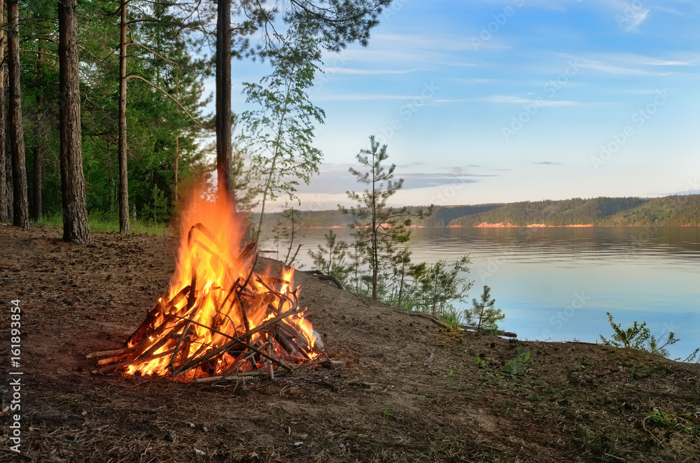Big night bonfire on the riverbank in the forest clearing, flames, sparks and fireplace. Big night bonfire on the riverbank in the forest clearing, flames, sparks and fireplace.