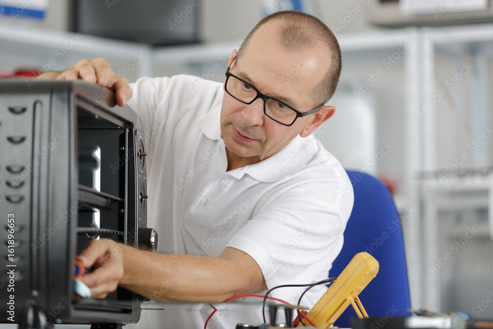 repairman with screwdriver fixing kitchen oven repairman with screwdriver fixing kitchen oven