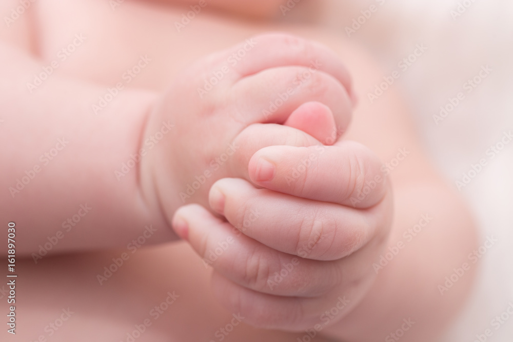 Newborn hands detail closeup. Lying on the bed and folding the hands Newborn hands detail closeup. Lying on the bed and folding the hands