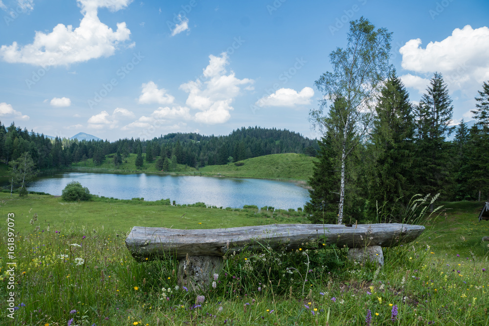 kleiner Bergsee mit Aussicht und Ruhebank