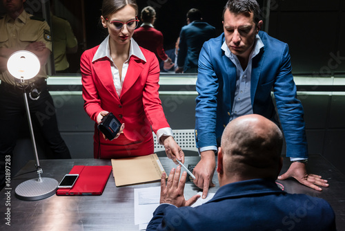 Фотография Two persuasive investigators trying to obtain a confession from a reluctant susp