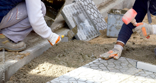 Photo Hands of a builder laying new paving stones carefully placing one in position on