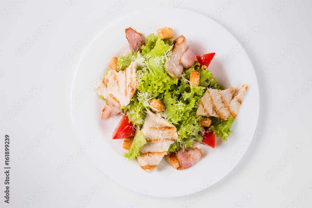 salad with bacon, tomatoes and croutons on a white plate (top view)
