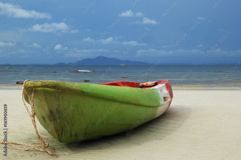 Travel to island Phi Phi, Thailand. The green-red-white boat on the sand beach with sea and a mountain and blue sky on background. Travel to island Phi Phi, Thailand. The green-red-white boat on the sand beach with sea and a mountain and blue sky on background.