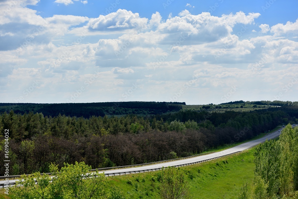 Landscape with a long road, clouds and forest