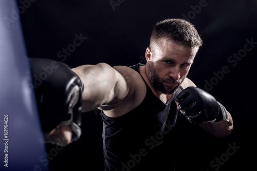 Studio shot of male boxer punching a boxing bag.  © Zoran Zeremski