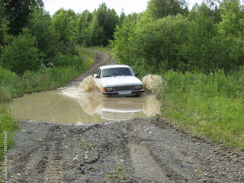 Car overcomes deep puddles. Bad roads in the north of the Ural Mountains