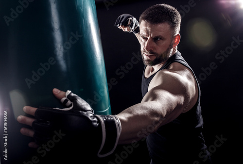 Studio shot of male boxer punching a boxing bag. 