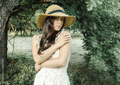 Beautiful girl in a hat on a background of a summer park