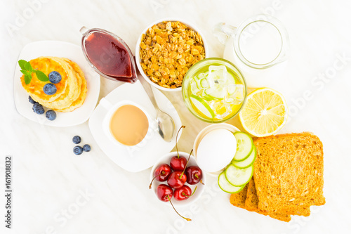 Homemade breakfast concept with granola, cottage cheese pancakes, detox water, egg and coffee on table