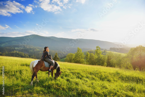 A woman is sitting on a horse in the mountains © sergo321