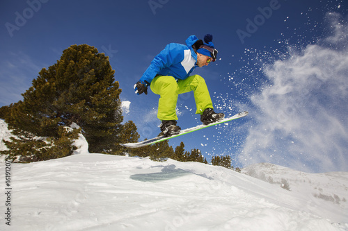 Snowboarder jumping through air in winter forest and snow