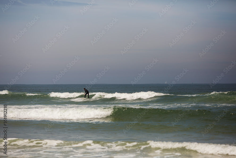 Student beginner  surfer trying to stay and ride small wave to shore in Atlantic ocean, Portugal