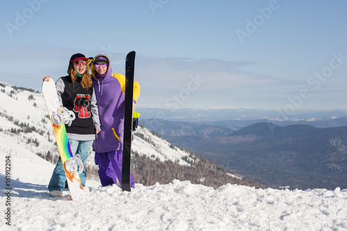 Skier and snowboarder together on mountain top, enjoy sunny holiday and going to freeride