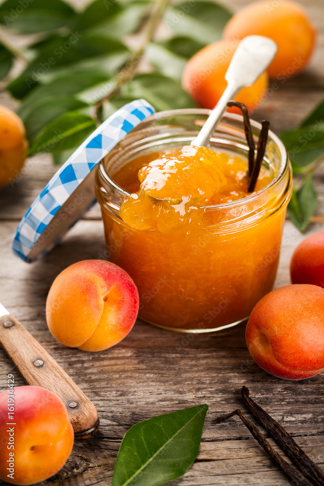 Tasty fruit orange apricot jam in glass jar with fruits and vanilla sticks on wooden table. Closeup. Tasty fruit orange apricot jam in glass jar with fruits and vanilla sticks on wooden table. Closeup.