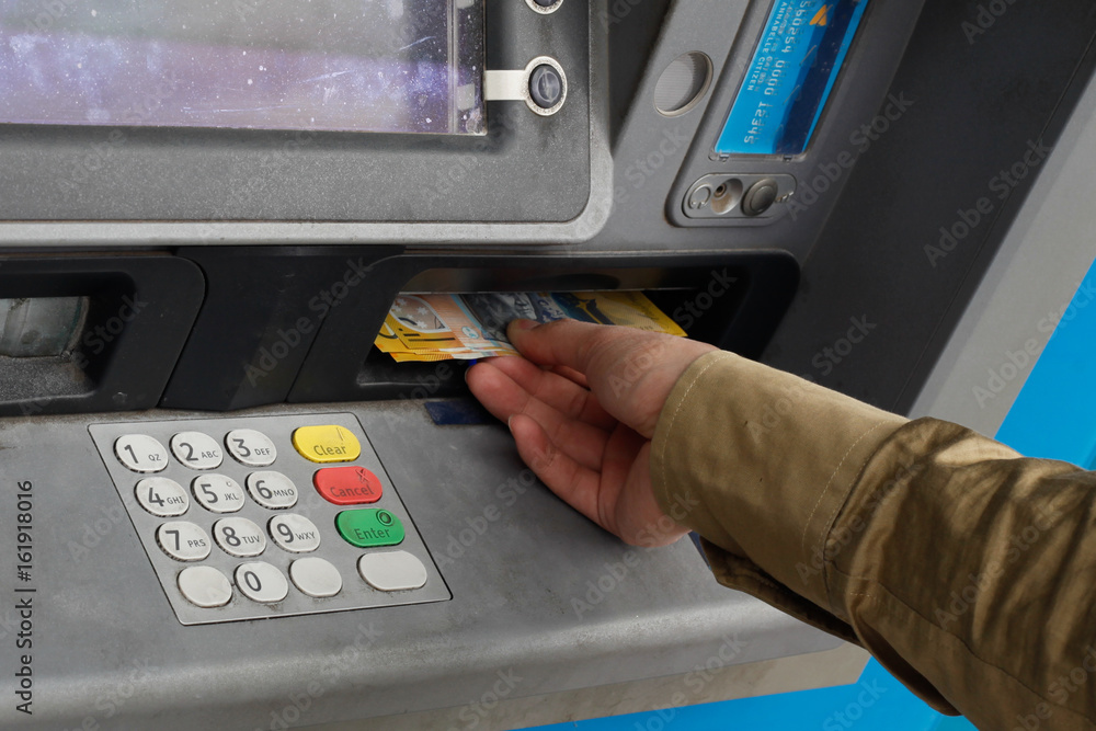 Male hand taking Australian money from an ATM Male hand taking Australian money from an ATM