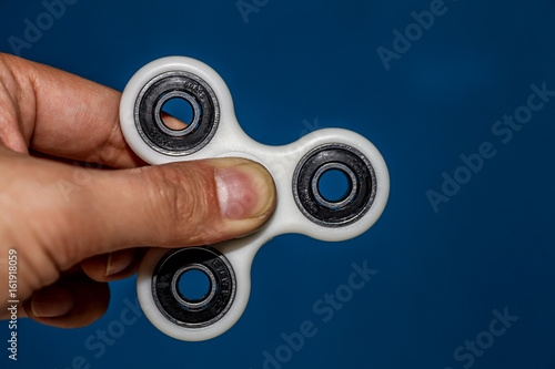 a hand holding a starionary fidget spinner on blue background photo