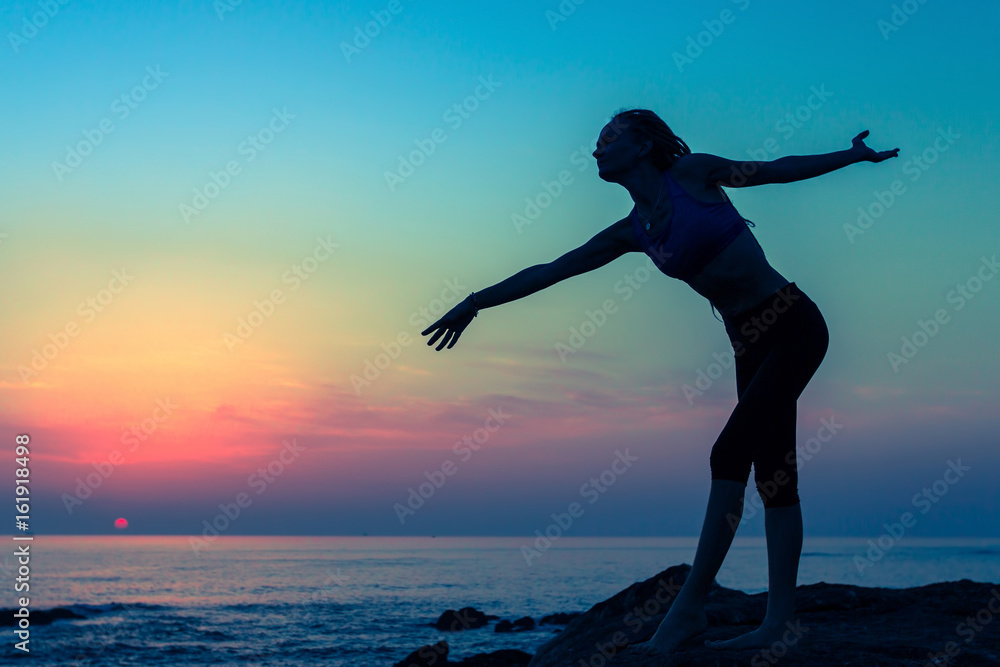 Dancing woman silhouette on the seaside during twilight.