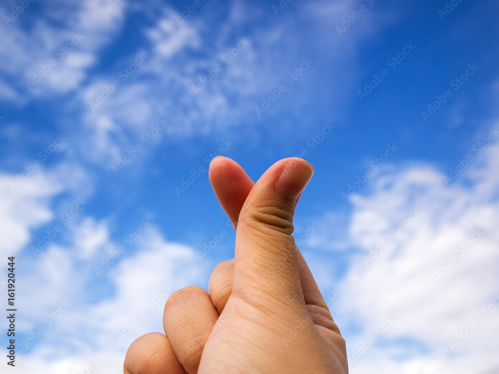 Close up action of young woman hand in mini heart by forefinger and thumb, Mini heart with blue sky, love symbolic of Korea. Close up action of young woman hand in mini heart by forefinger and thumb, Mini heart with blue sky, love symbolic of Korea.