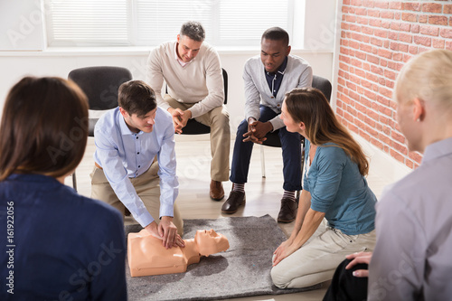 Male Instructor Showing CPR Training On Dummy
