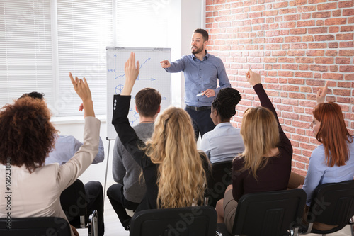 Group Of Businesspeople Raising Hands In Conference
