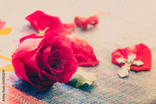 Fotografija Bright Red Rose with blur metal cross god background