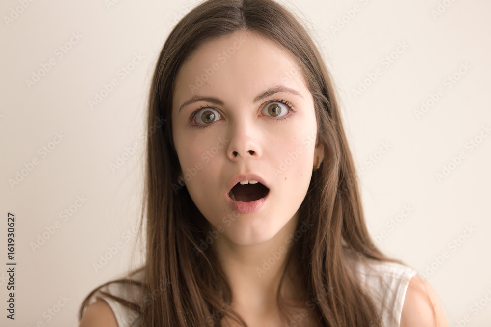 Headshot portrait of puzzled young woman. Attractive teen girl with confused  facial expression looking at camera with surprise. Pretty female feels  suddenly shocked or worried. Close up. Front view Stock Photo