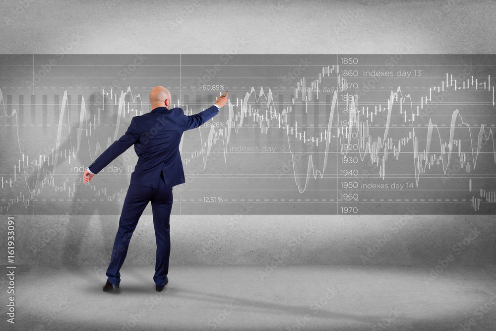 Man in front of a wall writing on a stock exchange interface - tradex concept Man in front of a wall writing on a stock exchange interface - tradex concept