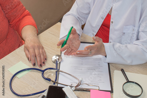 Female doctor holding application form while consulting patient