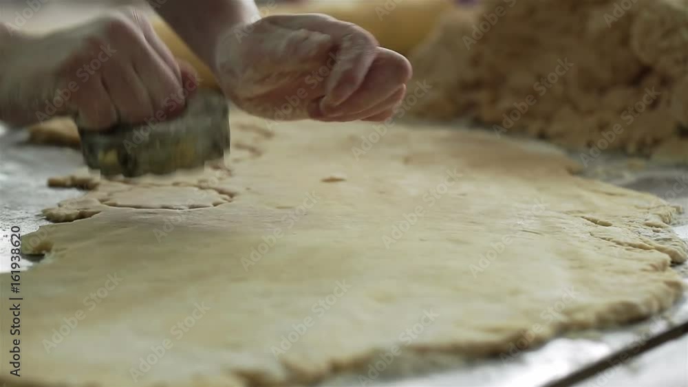 A woman uses a cookie cutter to cut circular shapes in dough. A woman uses a cookie cutter to cut circular shapes in dough.