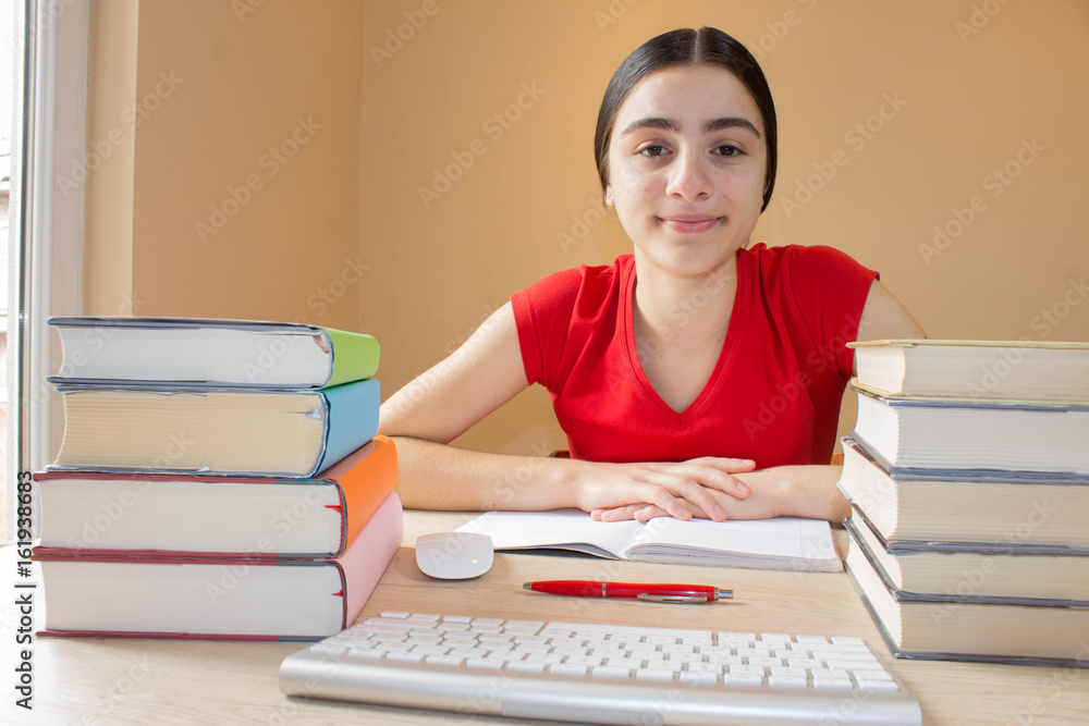 Girl doing her homework. School books on desk, education concept. Young Girl doing lessons at home Girl doing her homework. School books on desk, education concept. Young Girl doing lessons at home
