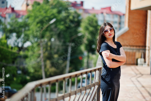 Brunette girl at black dress, sunglasses posing at street of city. © AS Photo Family