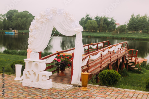The wedding composition of the signs and arch placed near the wooeden pier. photo