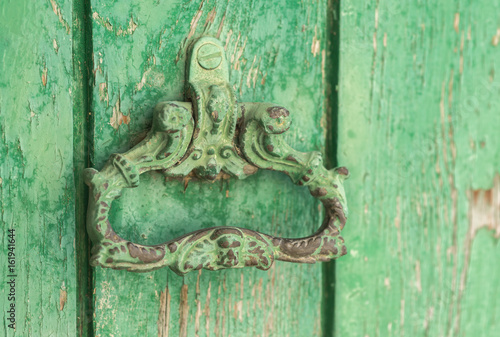 Closeup vintage antique Wooden door painted in worn green on a Country house door lock door handle and latch
