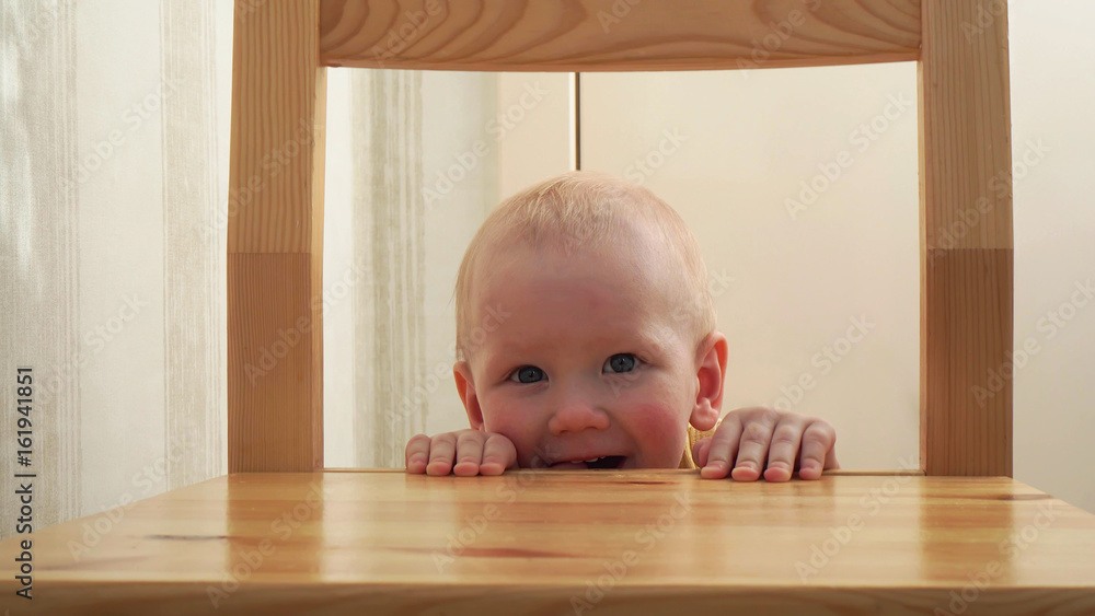 Cute little boy peeking out from behind a chair Cute little boy peeking out from behind a chair