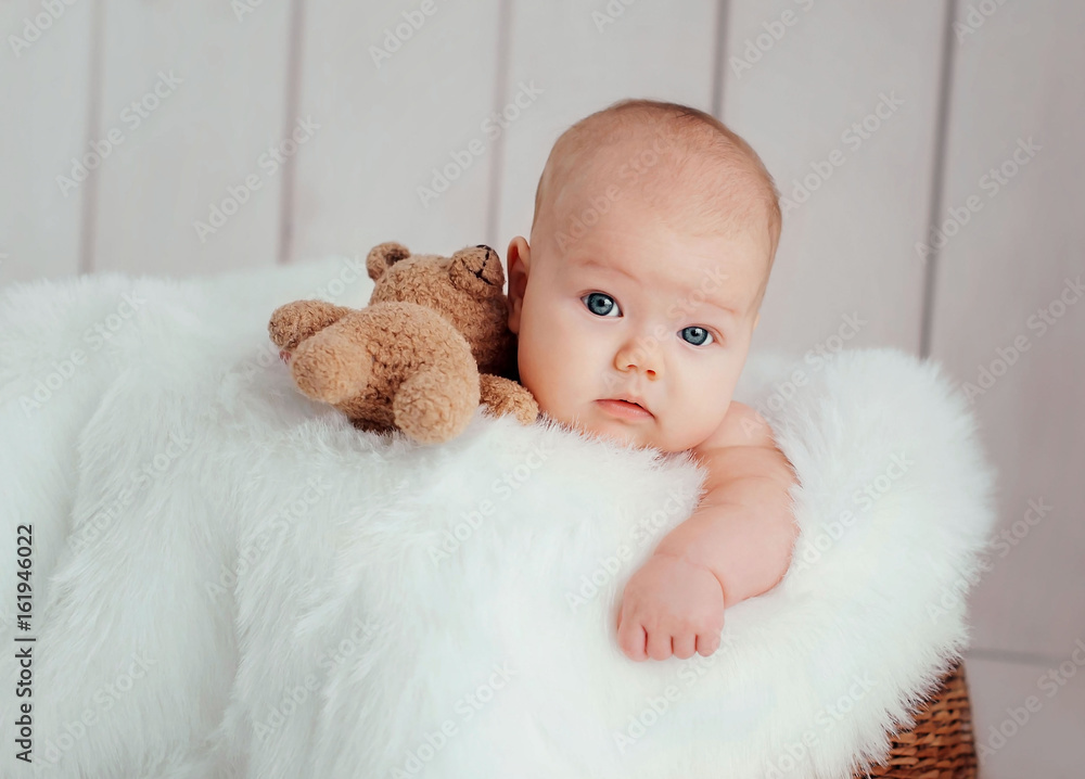 Cute newborn baby lying on fur blanket with toy Teddy Bear brown  