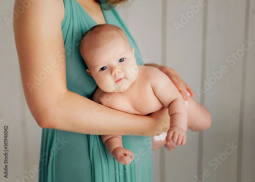 Mother holding a baby to prevent colic in his stomach. Mother's concern. Hands mom always cure the pain. photo