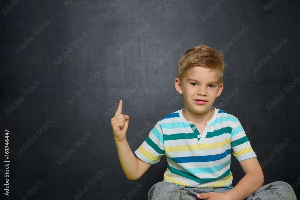 Boy posing with blackboard behind him