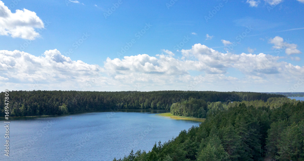 Picturesque view on the lake and forest at evening time just before the sunset. Sky and clouds reflected in water surface.Beautiful natural landscape. Panoramic view. The land of lakes. Europe.