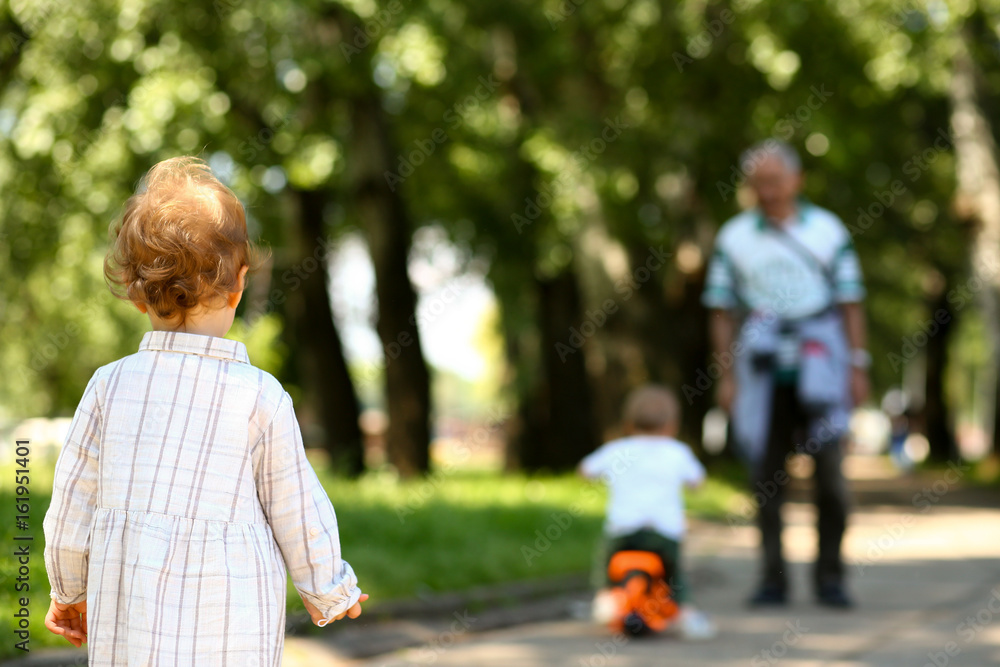 Little girl with curly hair stands on the road in park Little girl with curly hair stands on the road in park