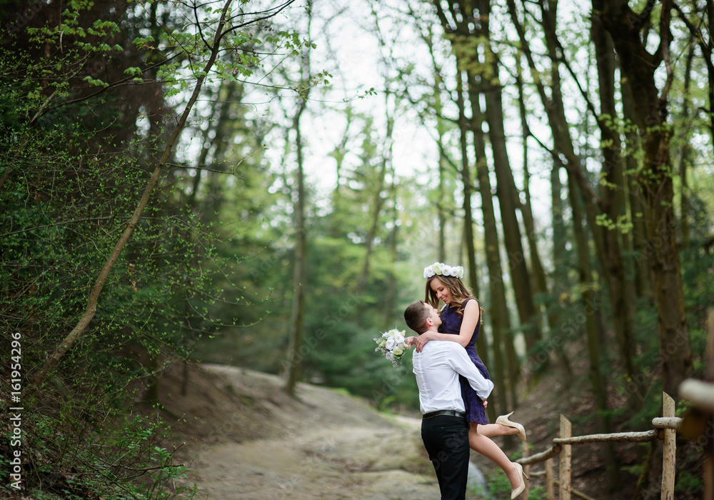 Groom holds bride in his arms standing in the forest Groom holds bride in his arms standing in the forest