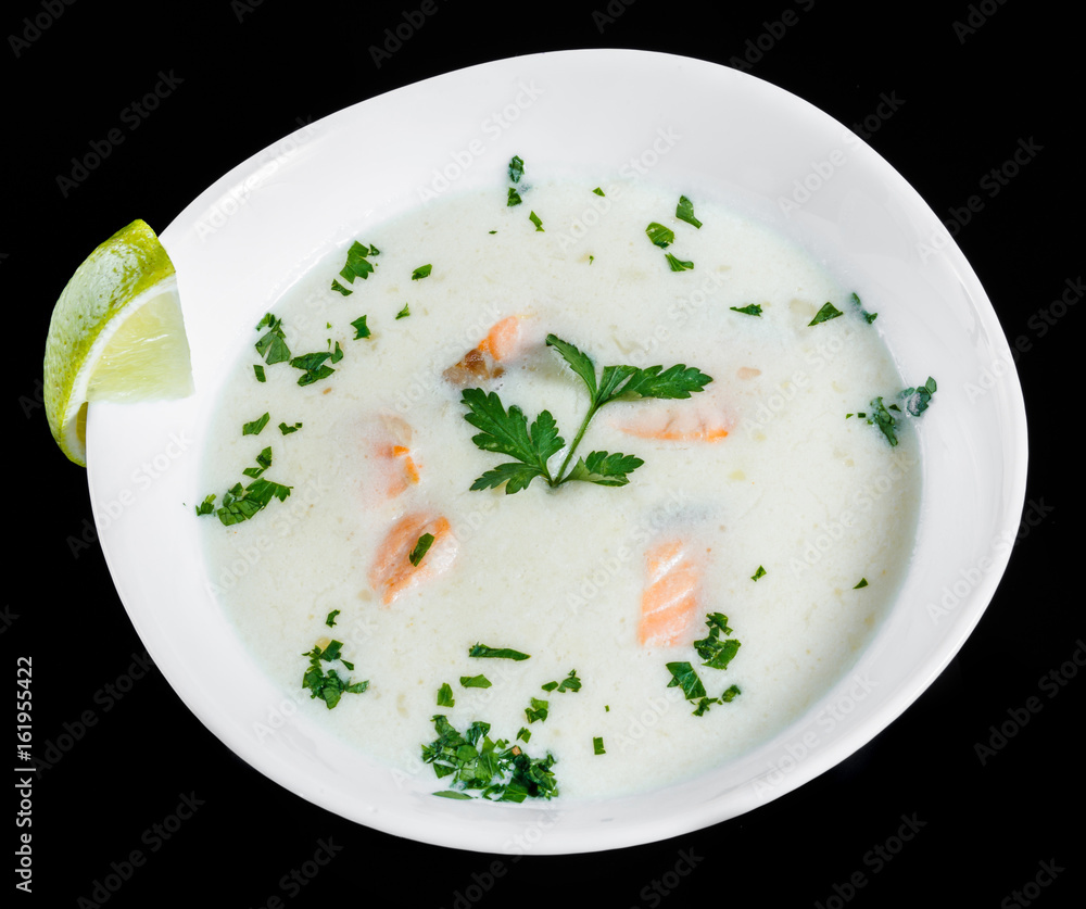 Fish soup with salmon and shrimps, parsley and lemon in bowl, isolated on black background, healthy food. Top view Fish soup with salmon and shrimps, parsley and lemon in bowl, isolated on black background, healthy food. Top view