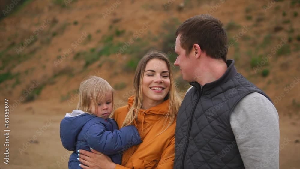 Slow motion shot of happy parents with little daughter and elder son enjoying evening outing together. Mother holding a sleepy kid Slow motion shot of happy parents with little daughter and elder son enjoying evening outing together. Mother holding a sleepy kid