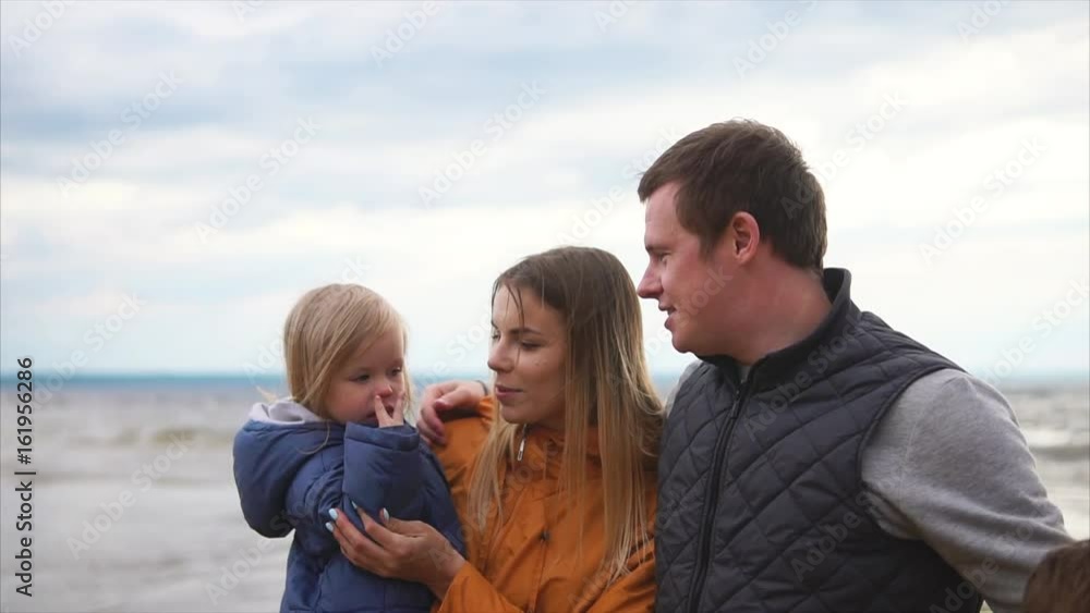 Family leisure. Family of four standing on a beach at cold windy weather. Woman, man, girl and boy Family leisure. Family of four standing on a beach at cold windy weather. Woman, man, girl and boy